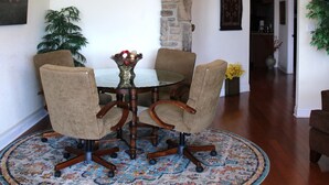 A dining area with a round table, four chairs, a chandelier, a stone wall, and a patterned rug. - Lake Views from this Balcony are amazing! (Hot Springs)