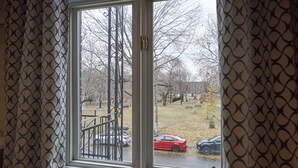 A window with a view of a park and parked cars.