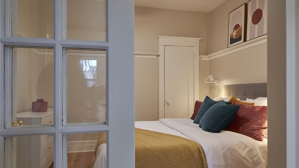 A bedroom with a bed, bedside table, and a wardrobe.