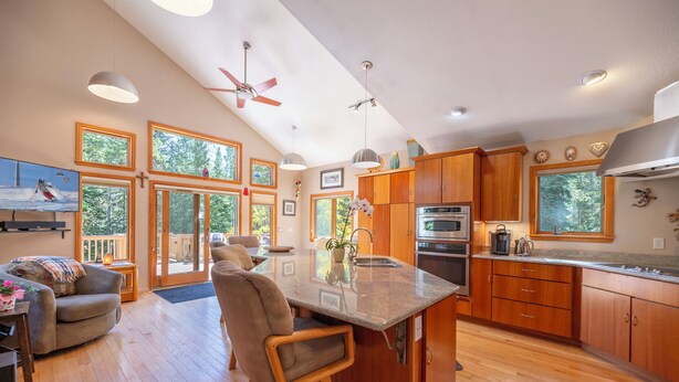 A spacious kitchen with wooden cabinets, a large island, and a dining area with a sofa and chairs. - Peak 7, dog friendly fenced in yard, hot tub, pool table & dedicated work space (Breckenridge)