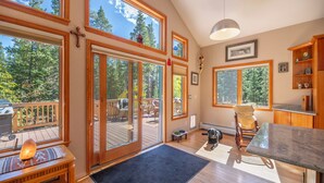 A spacious room with large windows, a wooden deck, and a cozy seating area. - Peak 7, dog friendly fenced in yard, hot tub, pool table & dedicated work space (Breckenridge)