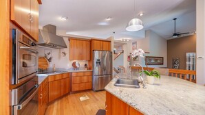 A modern kitchen with wooden cabinets, stainless steel appliances, a marble countertop, and a ceiling fan. - Peak 7, dog friendly fenced in yard, hot tub, pool table & dedicated work space (Breckenridge)