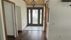 Un'ampia sala con pavimenti e soffitto in legno, che conduce a una porta con un pannello di vetro.
