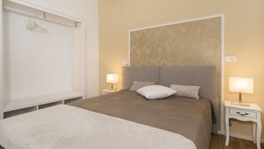 Une chambre à coucher bien rangée, avec un grand lit, deux tables de chevet dotées de lampes et une armoire.