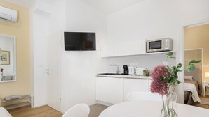 Une cuisine moderne avec des meubles blancs, un four à micro-ondes et un téléviseur à écran plat.