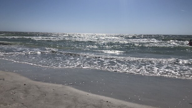 A beach with waves and a clear sky.