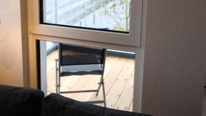 Ein Zimmer mit großem Fenster und Balkon mit Stuhl.