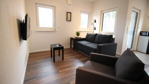 Ein Wohnzimmer mit einer Couch, einem Couchtisch und einem an der Wand befestigten Fernseher.
