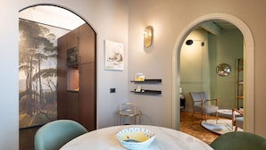 A modern dining area with a round table, chairs, and a bowl on the table. There is a wall with a framed picture and a shelf with books. - New Listing: Oltrarno Nest with Court, San Frediano area (Firenze)