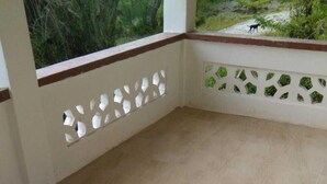 A balcony with tiled flooring and a white wall with decorative cutouts. - Spacious 2-bed House in Carriacou (Hillsborough)
