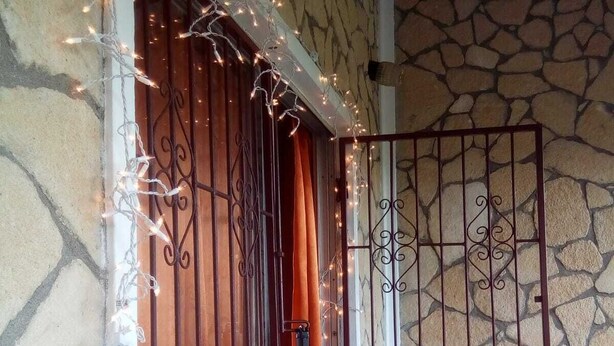 A stone wall with a metal gate and a chair. - Spacious 2-bed House in Carriacou (Hillsborough)