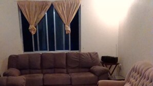 A living room with a brown sofa set, a coffee table, and a TV stand. - Spacious 2-bed House in Carriacou (Hillsborough)