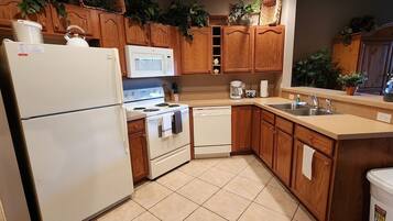 A kitchen with wooden cabinets, a white refrigerator, a microwave, a stove, a dishwasher, and a sink.