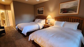 A hotel room with two beds, a nightstand with a lamp, and two framed pictures on the wall.