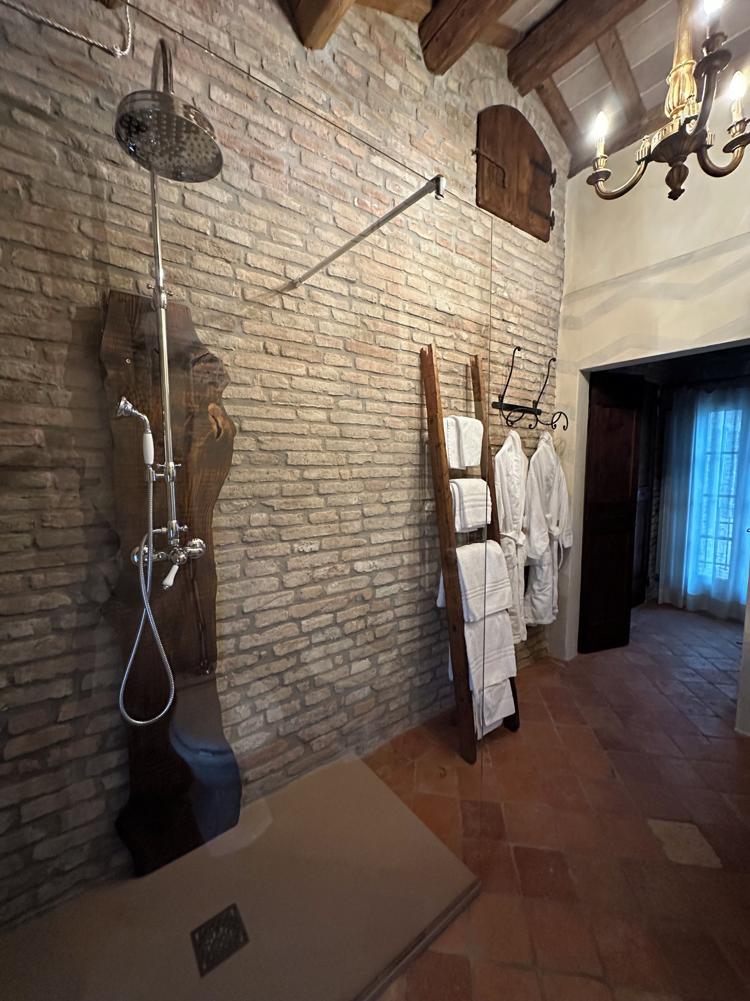Un baño con ducha, un perchero para toallas y un banco de madera.