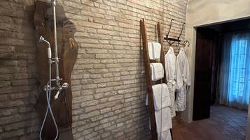 Un baño con ducha, un perchero para toallas y un banco de madera.
