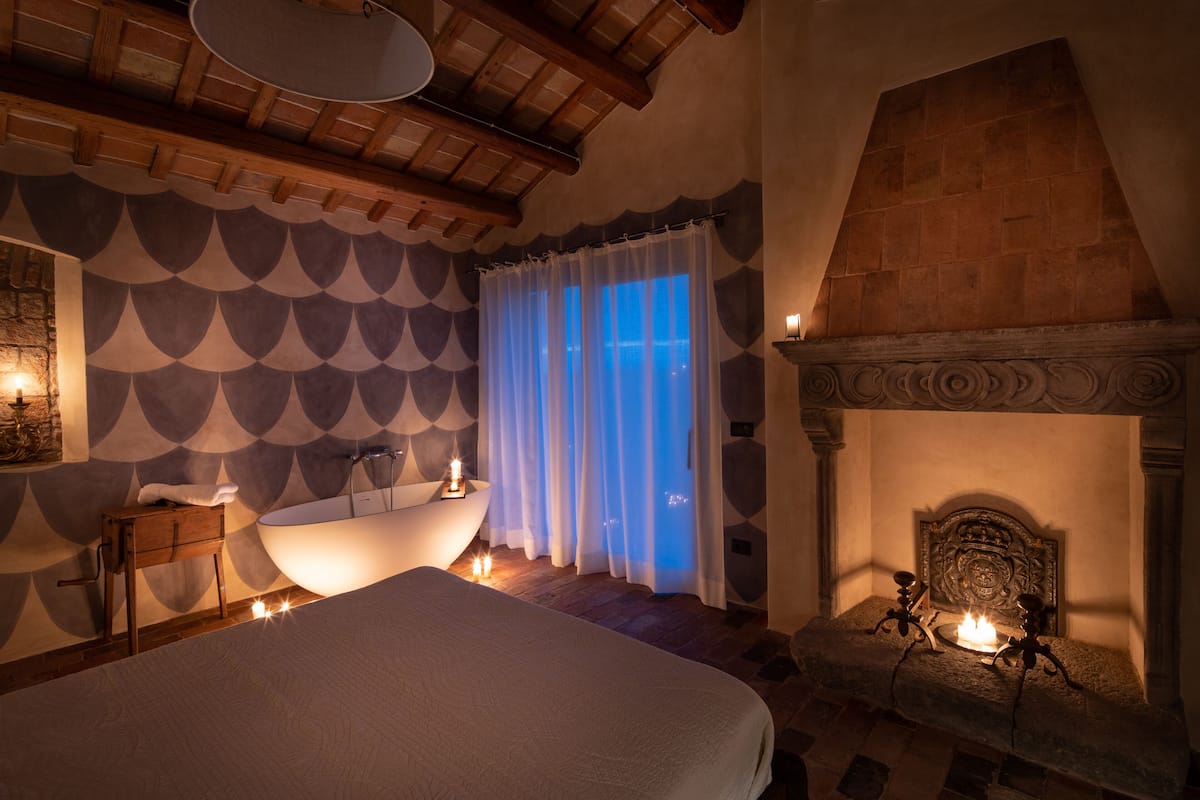 Un dormitorio con una cama grande, una bañera y una chimenea.