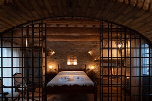 Una habitación rústica con una cama, paredes de madera y una entrada con rejas.