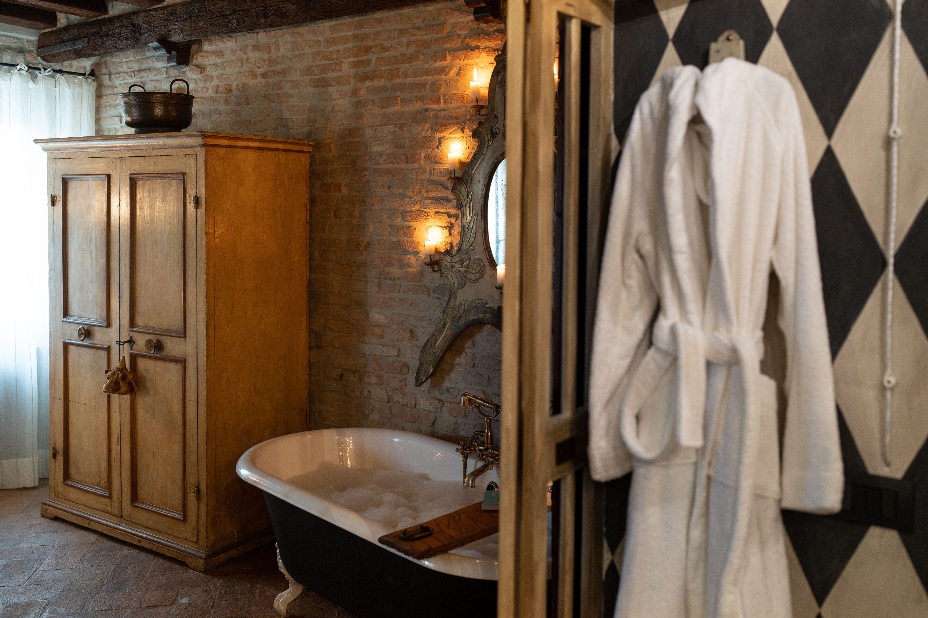 Une salle de bain avec un meuble en bois, une baignoire sur pieds et un miroir doté d’un cadre décoratif.