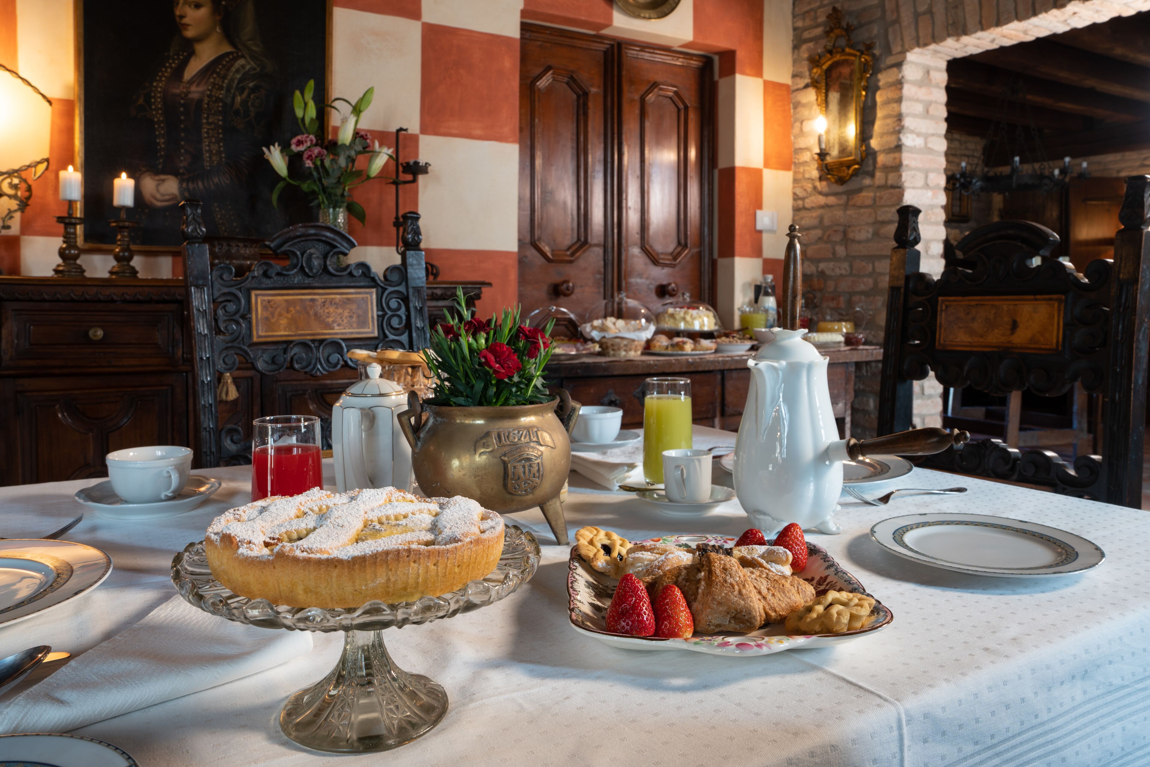 Une table mise pour le petit-déjeuner, avec une variété de viennoiseries, un vase rempli de fleurs et une table à manger traditionnelle.
