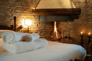 Una habitación acogedora con pared de ladrillo, chimenea y cama con toallas enrolladas.