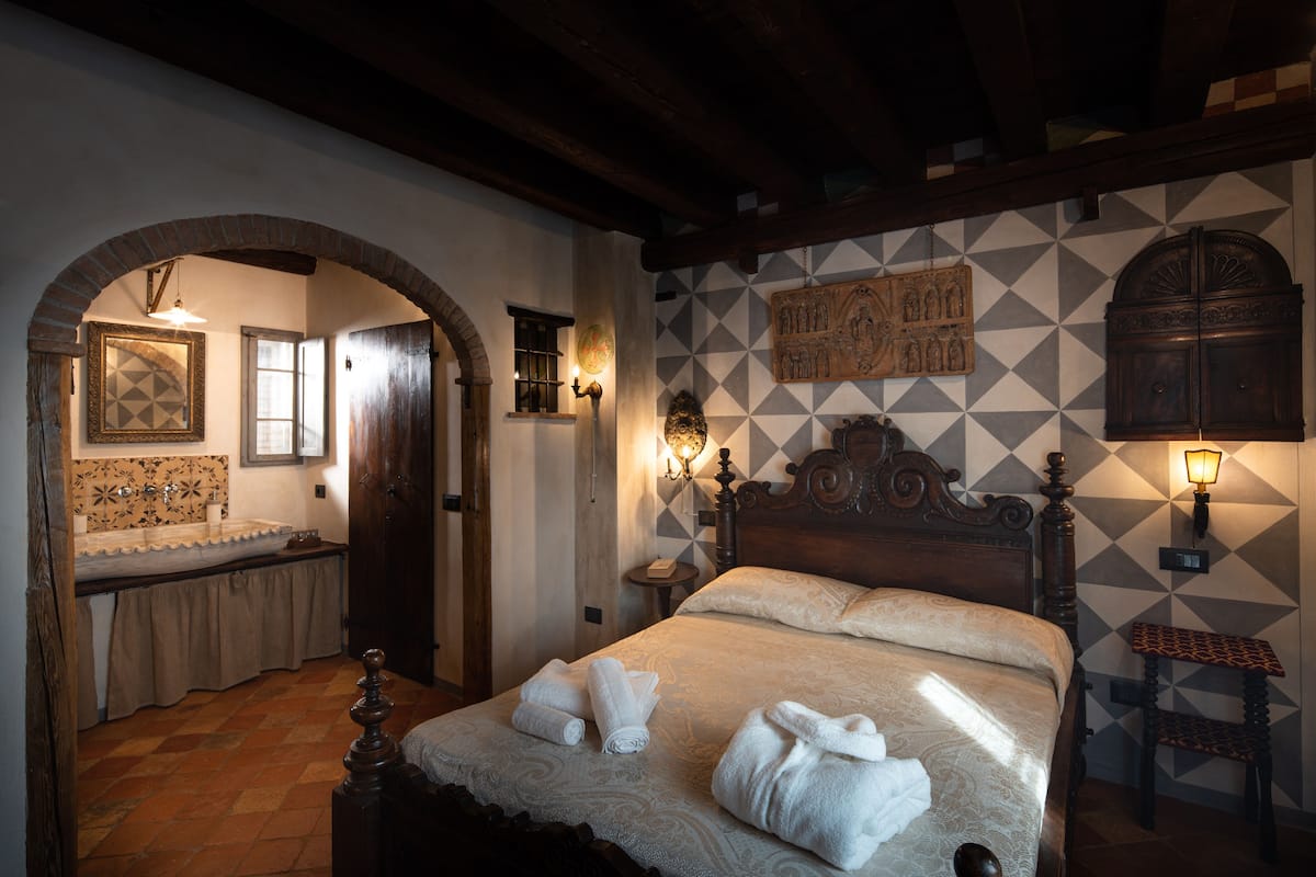 Un dormitorio con una cama grande, cabecera de madera, mesita de noche, lámpara de pared y pared con diseño.