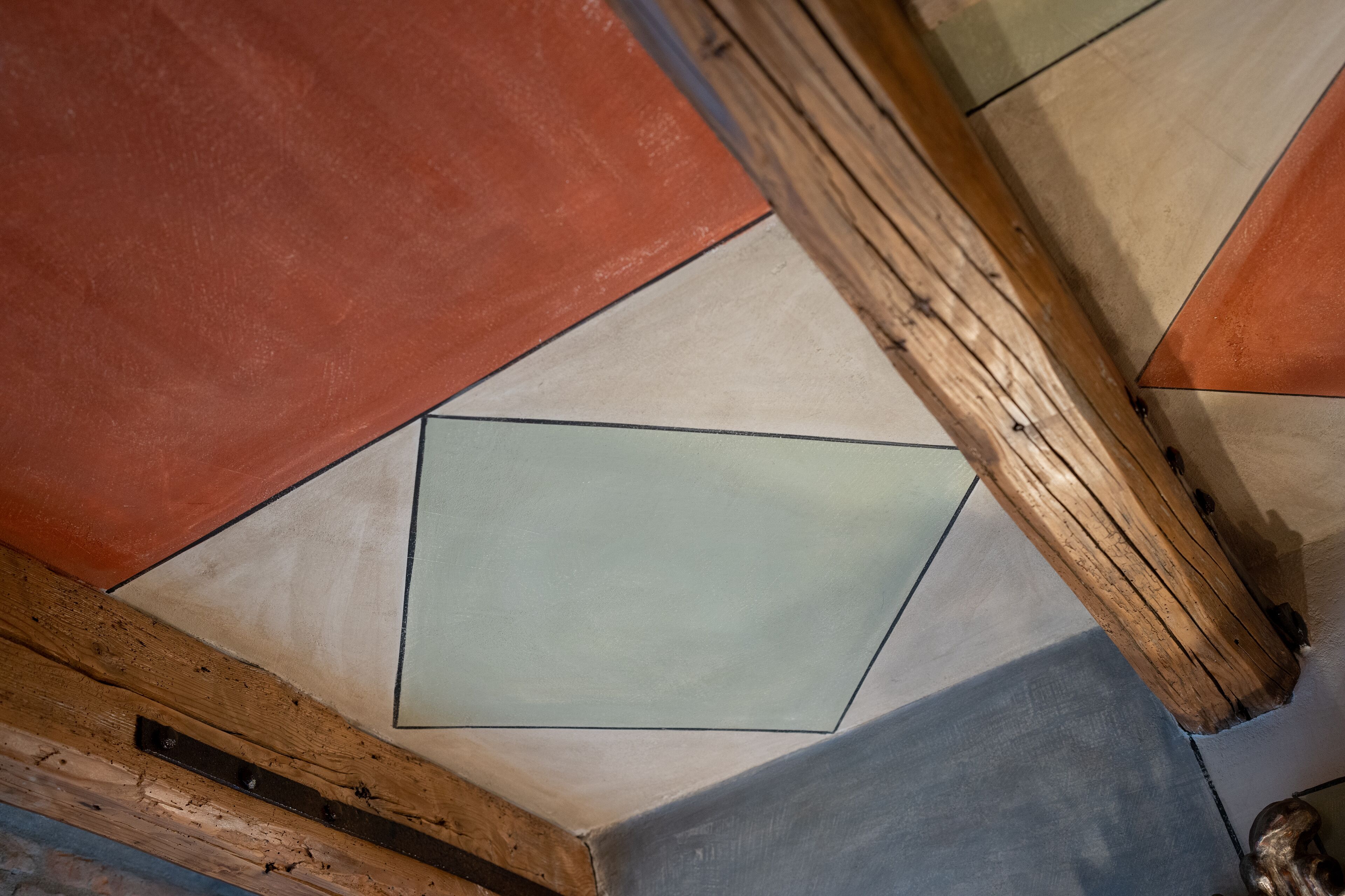 A ceiling with geometric patterns and wooden beams.