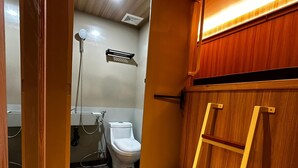 Un baño pequeño con inodoro, ducha y una escalera de madera.