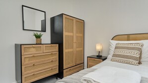 A bedroom with a bed, a nightstand, a dresser, a mirror, and a wall-mounted plant. - The Penthouse In Bonchurch  (Ventnor)