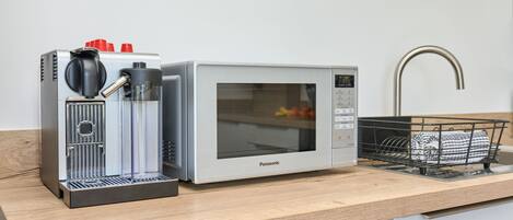 A kitchen with a coffee maker, microwave, and dish rack.
