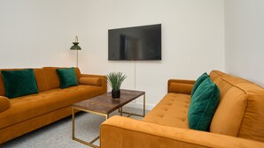 A modern living room with two mustard-colored sofas, a wooden coffee table, and a green floor lamp. - The Penthouse In Bonchurch  (Ventnor)