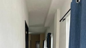A narrow hallway with a tiled floor, a dining area with a table and chairs, and a blue curtain on the right. - Oasis Apartment (Puerto Vallarta)