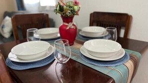 A dining table set with plates, a glass, and a vase with flowers. - Oasis Apartment (Puerto Vallarta)