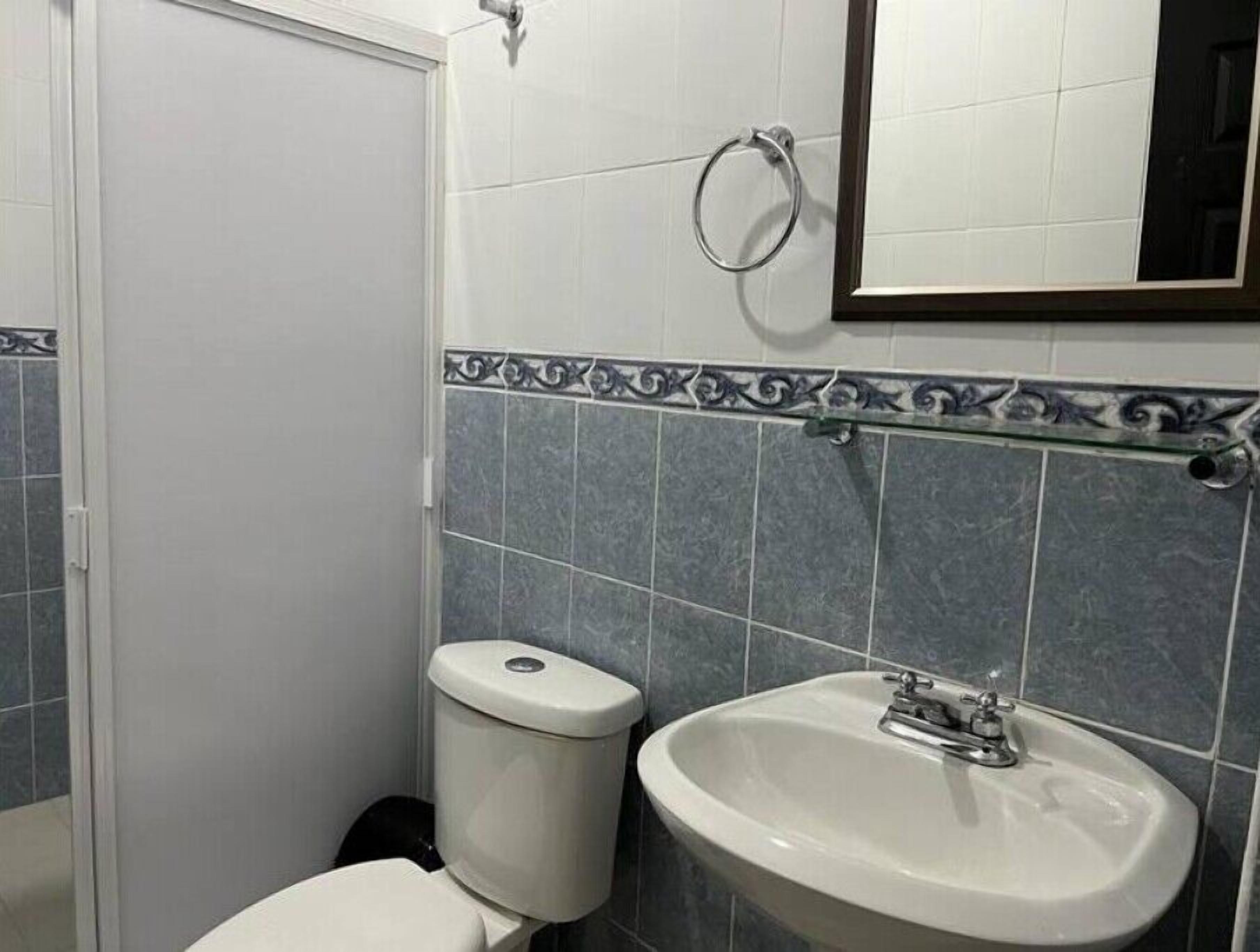 Une salle de bain avec des toilettes, un lavabo et un miroir au-dessus du lavabo.