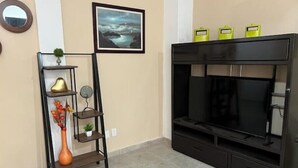 A living room with a black entertainment center, a decorative shelf with vases, and a framed picture on the wall.