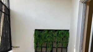 Un petit balcon avec une table ronde et deux chaises, un mur végétal et un sol carrelé.