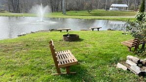 Een park aan het meer met een houten bank, een picknicktafel en een vuurplaats.