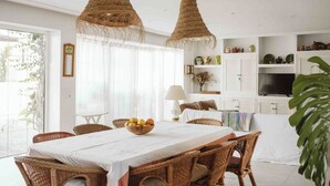 A dining area with a table set for four, surrounded by wicker chairs, under woven pendant lights. - Alojamiento Rural Para Grupos DE 20 Personas (BARBATE)