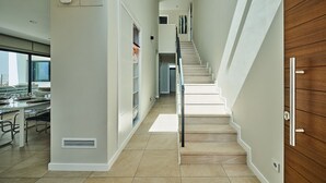 Ein modernes Interieur mit einer Treppe, einem Essbereich und Blick durch ein großes Fenster.