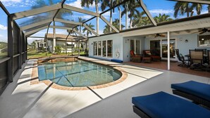 Ein überdachter Pool mit Blick auf Palmen und ein Gebäude im Hintergrund.