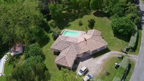 Luchtbeeld van een huis met een zwembad, omringd door weelderige begroeiing.