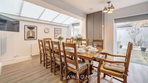 A dining area with a wooden table and chairs, a skylight, and a view of the outside. - Villa Living by Lawsons (Windsor)