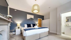 A modern bedroom with a large bed, bedside lamps, a wall-mounted artwork, and a unique ceiling light fixture. - Villa Living by Lawsons (Windsor)
