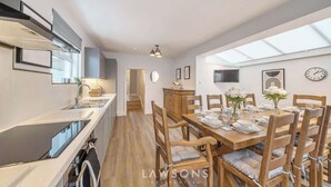 A modern kitchen with a dining area, wooden chairs, and a large window. - Villa Living by Lawsons (Windsor)