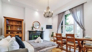 Een moderne woonkamer met een open haard, houten meubels en een eethoek met een tafel en stoelen.
