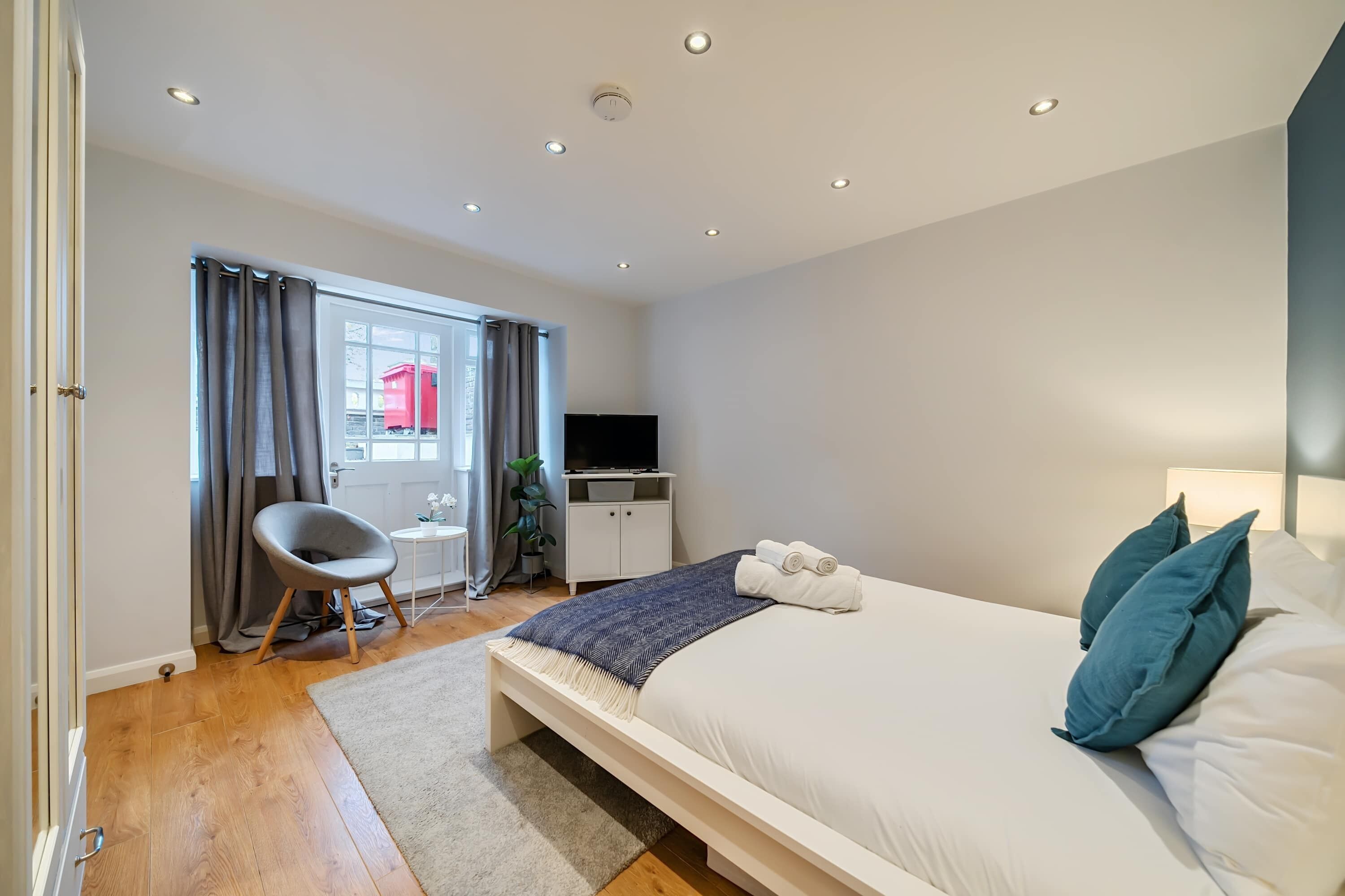 A modern bedroom with a bed, a desk, and a TV.