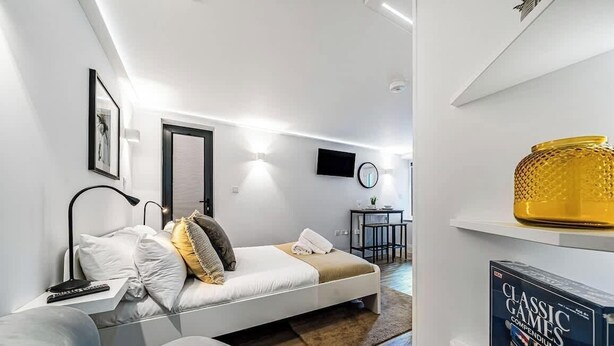 A modern bedroom with a bed, bedside table, lamp, and a TV.