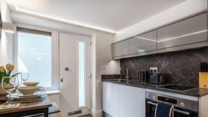 A modern kitchen with white cabinets, a marble backsplash, and stainless steel appliances.