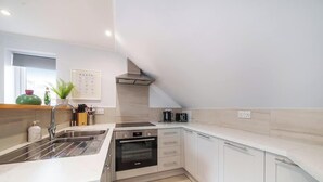 A modern kitchen with a stainless steel sink, a Bosch oven, and a compact dishwasher.