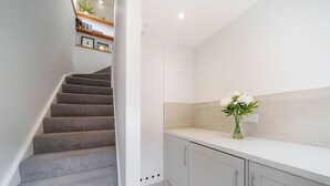 A staircase leading to a kitchen area with a white countertop and a vase of flowers.